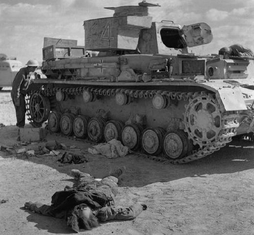 Un Panzer IV puesto fuera de combate durante la Operación Crusader es observado por un soldado del 8º Ejército Británico. En el suelo el cadáver de uno de los tripulantes del tanque