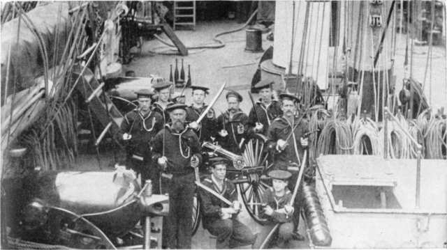 Marinos en una foto preparada, junto a una Gatling de 10 cañones a bordo del USS Alliance